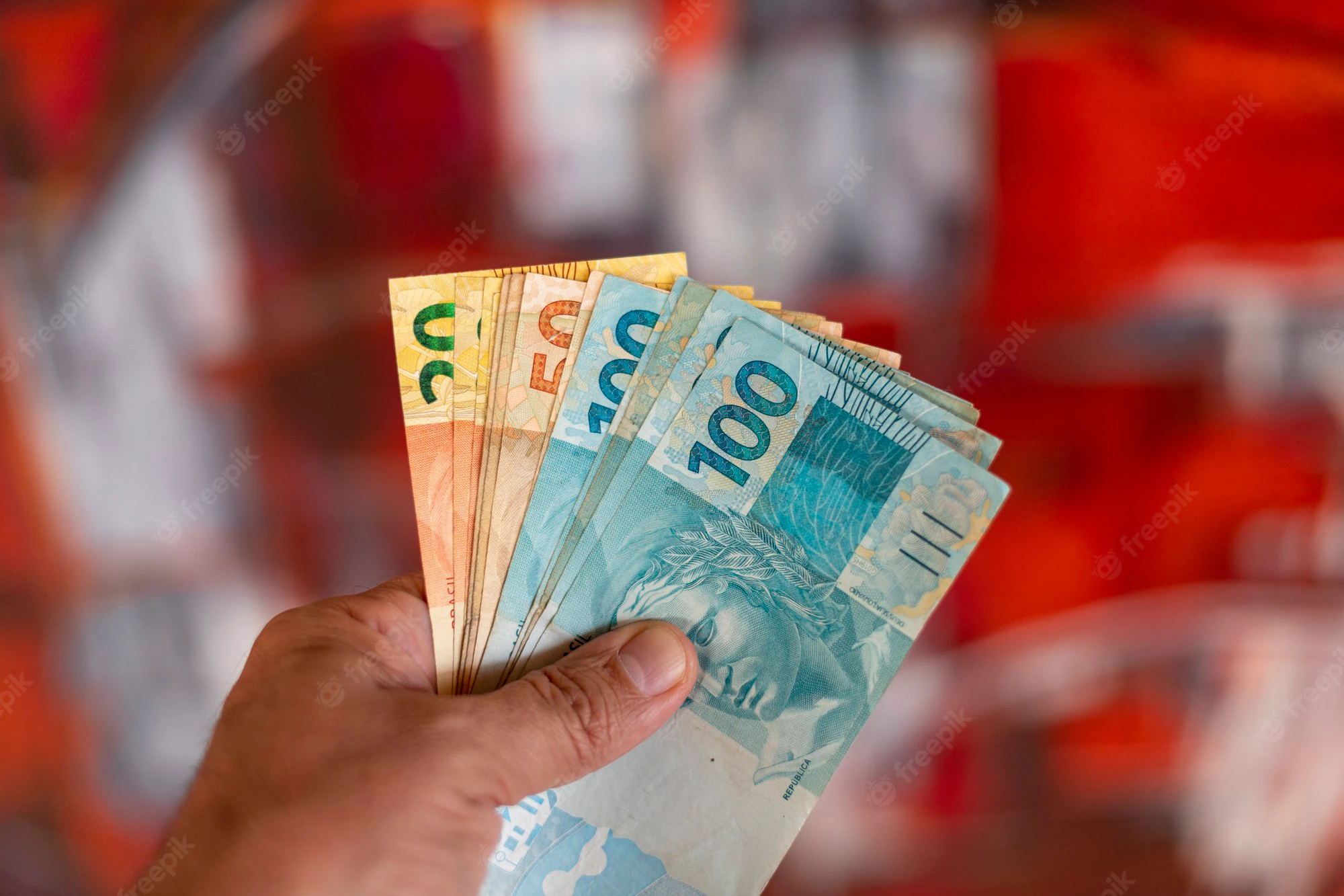 notas de dinheiro brasileiro na mao com fundo vermelho turva 146714 2321
